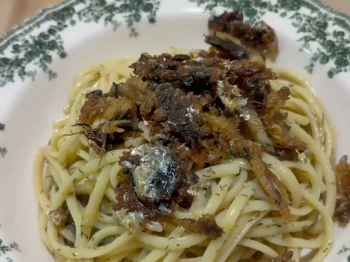 A plate of spaghetti with sardines and a crisp sardine crumb